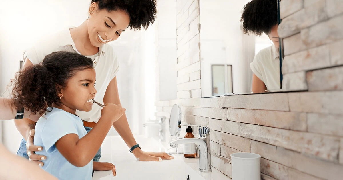 Family oral care routine: Mom guiding child's brushing to maintain space after early tooth loss – supporting space maintainers at Dental Smart Kids in Frisco, TX