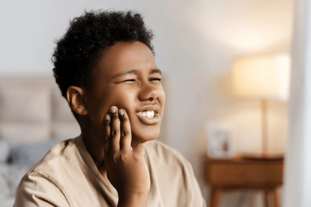 Pediatric dental abscess Frisco TX child holding jaw in pain at Dental Smart Kids