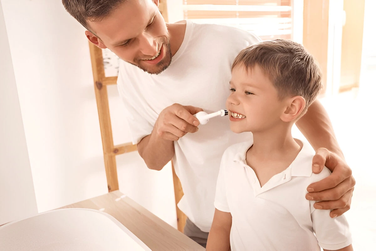 Oral cancer screening at Dental Smart Kids with parent brushing child’s teeth.