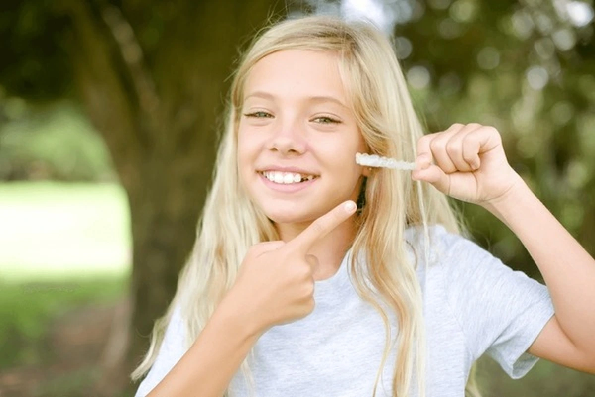 Invisalign for kids Frisco TX at Dental Smart Kids: happy girl brushing teeth ready for clear aligners