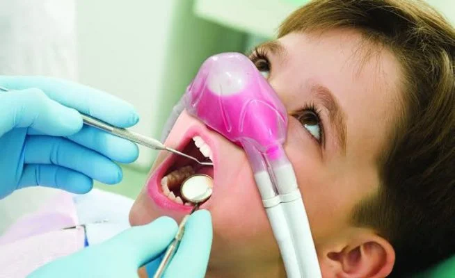 Oral conscious sedation Frisco TX child receiving dental exam with pink nitrous oxide mask at Dental Smart Kids
