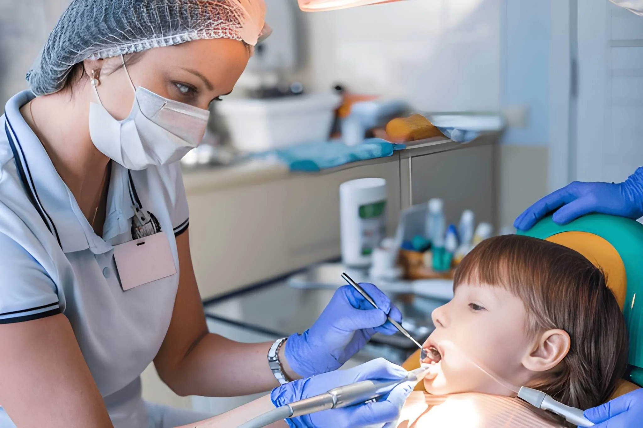 Pediatric oral surgery Frisco, TX: assistant using handpiece on calm boy in gentle procedure at Dental Smart Kids