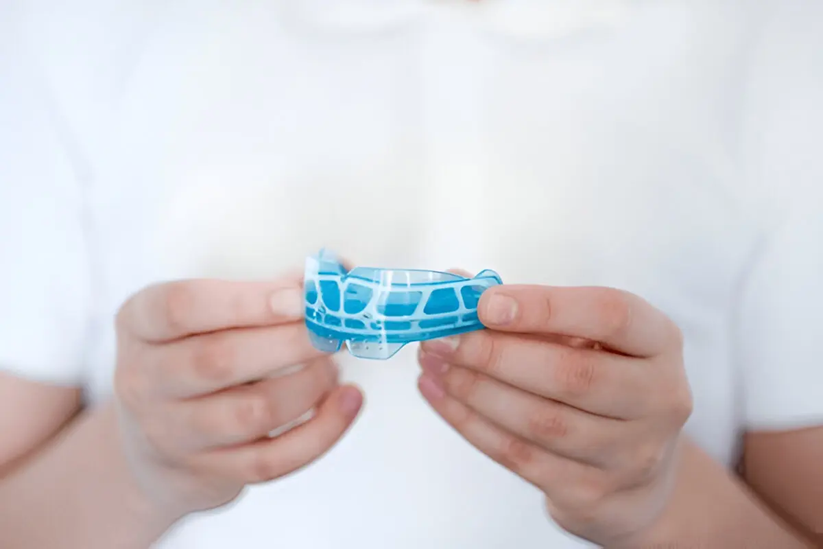 Kids mouthguards Frisco TX: custom blue sports guard held by dentist at Dental Smart Kids